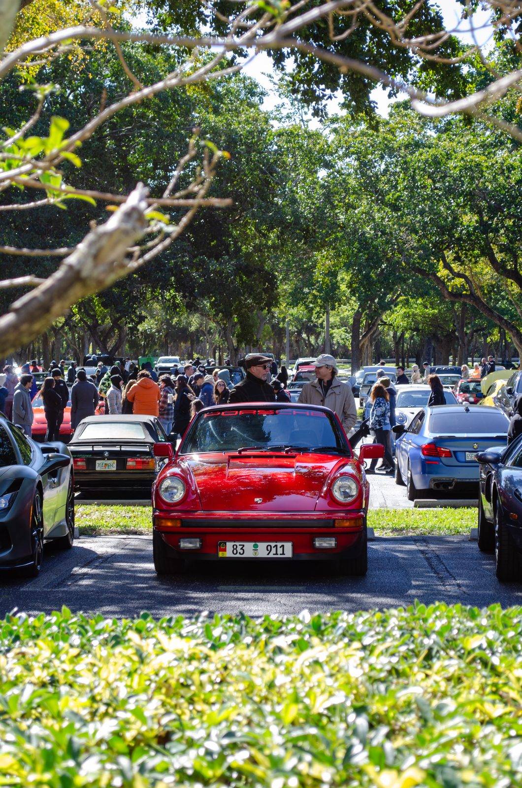 A classic 911 rolling through a crowded car meet